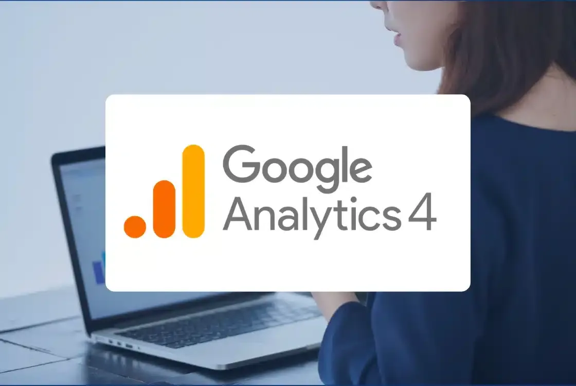 The Google Analytics 4 logo in front of a woman working on a laptop