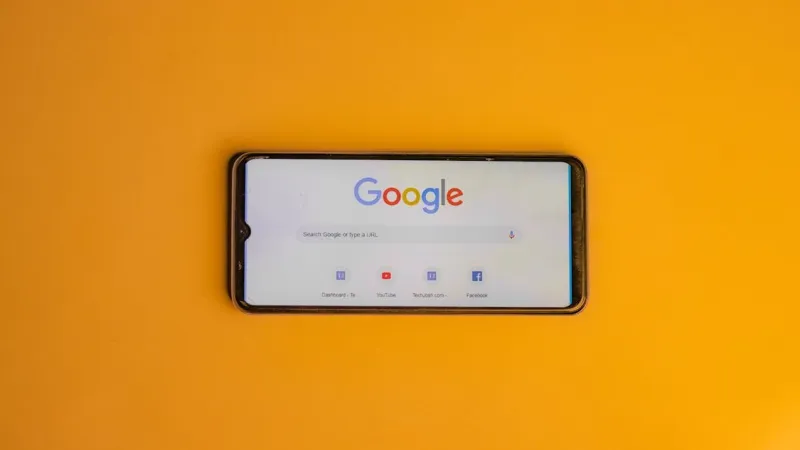 Smartphone showing the Google search page, lying on a yellow background