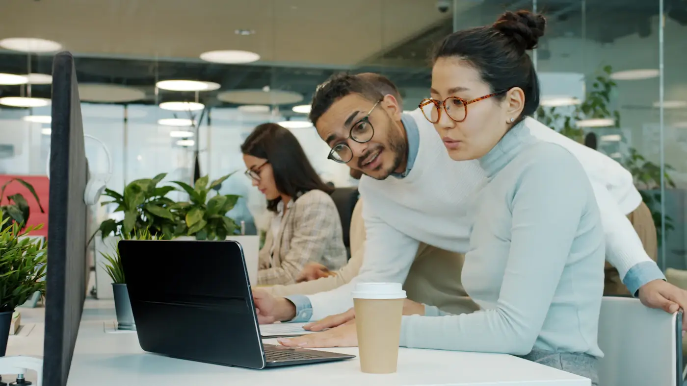 Two colleagues talking in front of a laptop